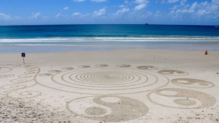 yin and ynag artwork on a beach