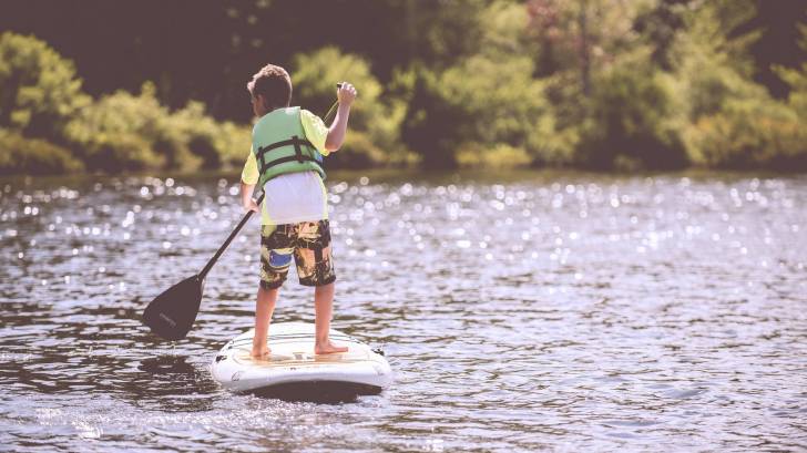 boy paddle boarding on a lake