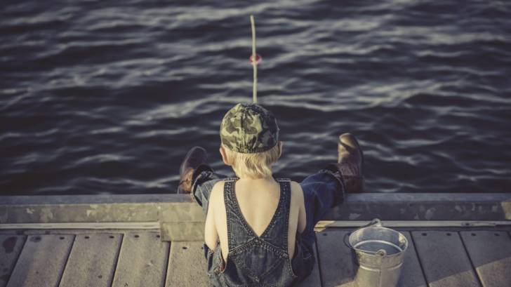 young boy fishing off the end of a dock