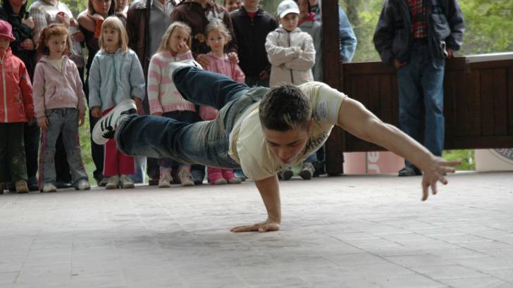 young man break dancing in front of group of teens