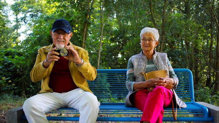 grandparents sitting on a bench taking photos