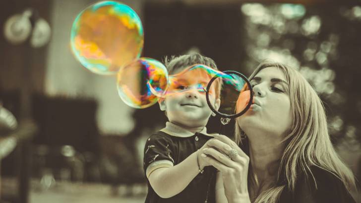 mom blowing bubbles with son who is happy and healthy