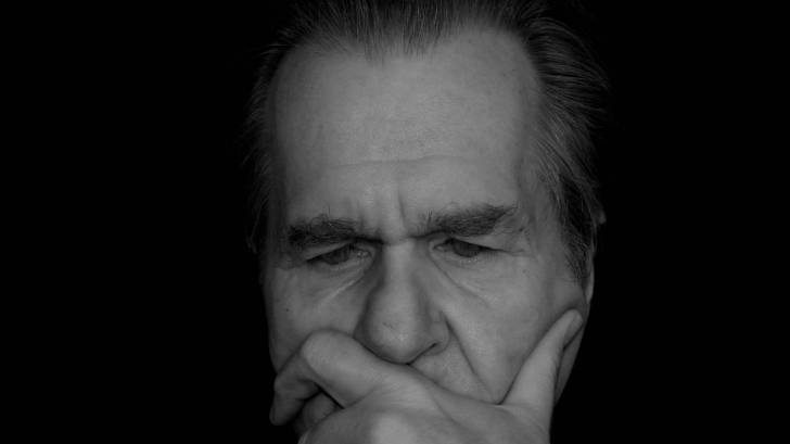 man thinking holding his hand over his face