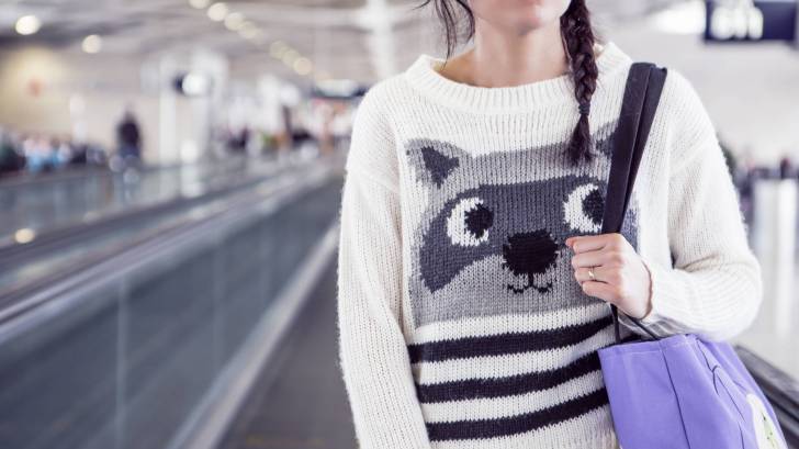 women on airport walkway with funny sweater and eyes looking up
