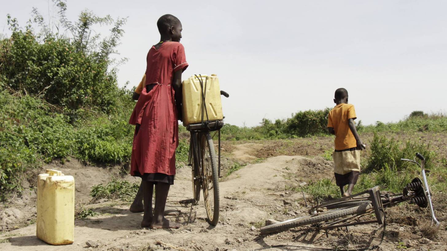 ugandan mom and son riding bikes to get fresh water
