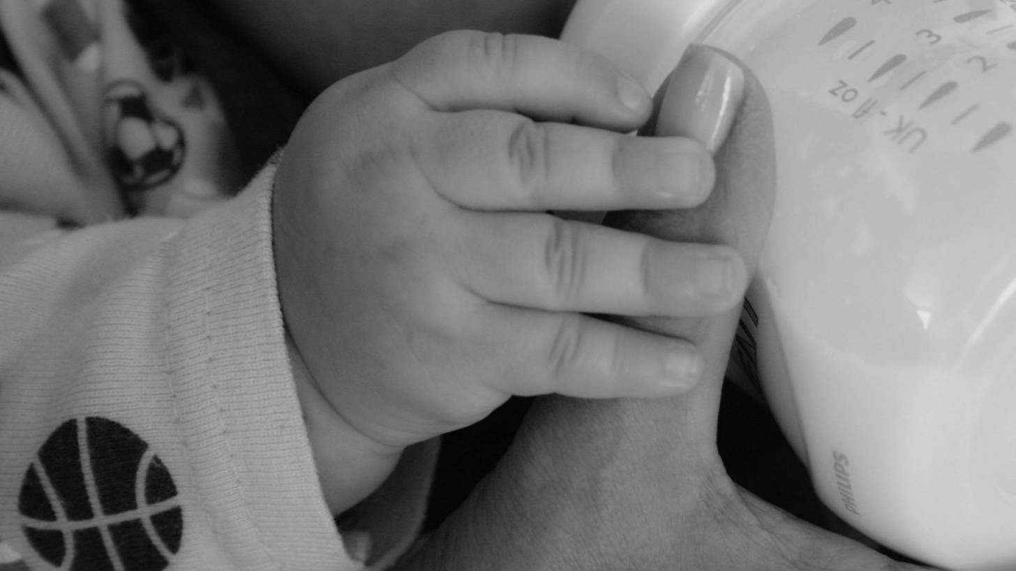 baby holding moms thumb while eating a bottle