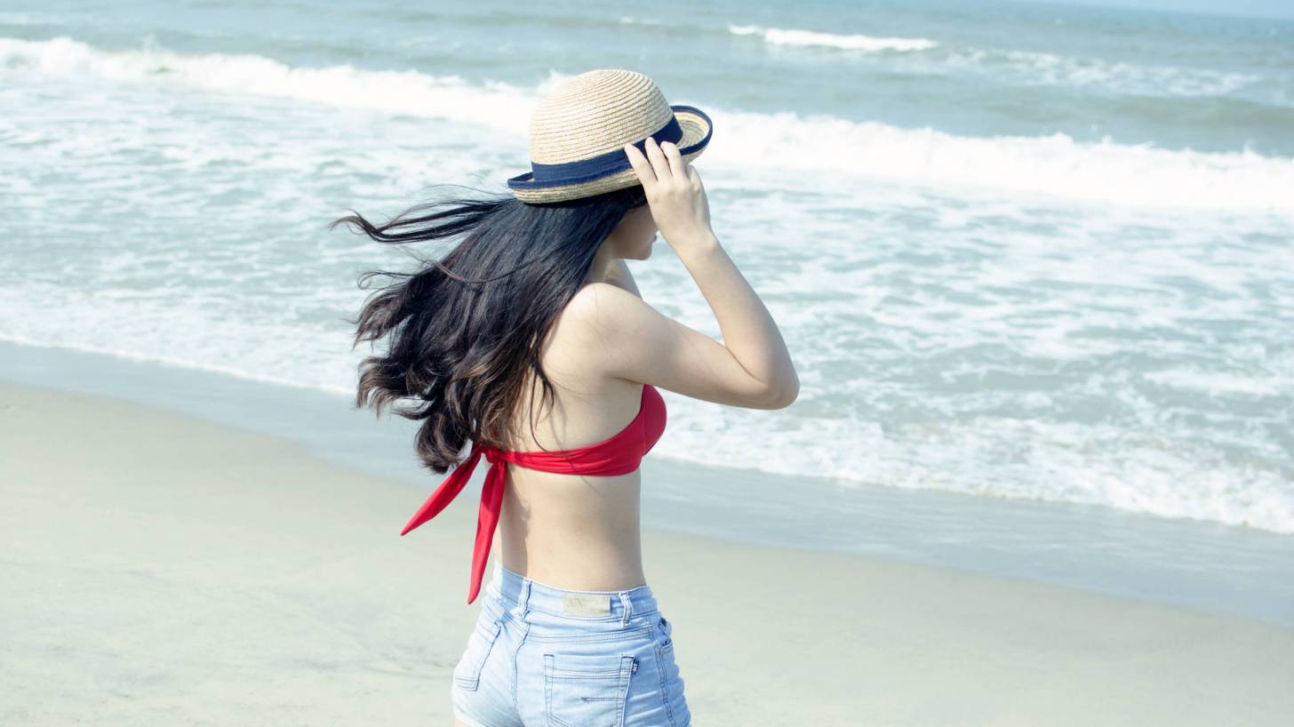 young girl on beach, fit, this with shorts and red top and hat