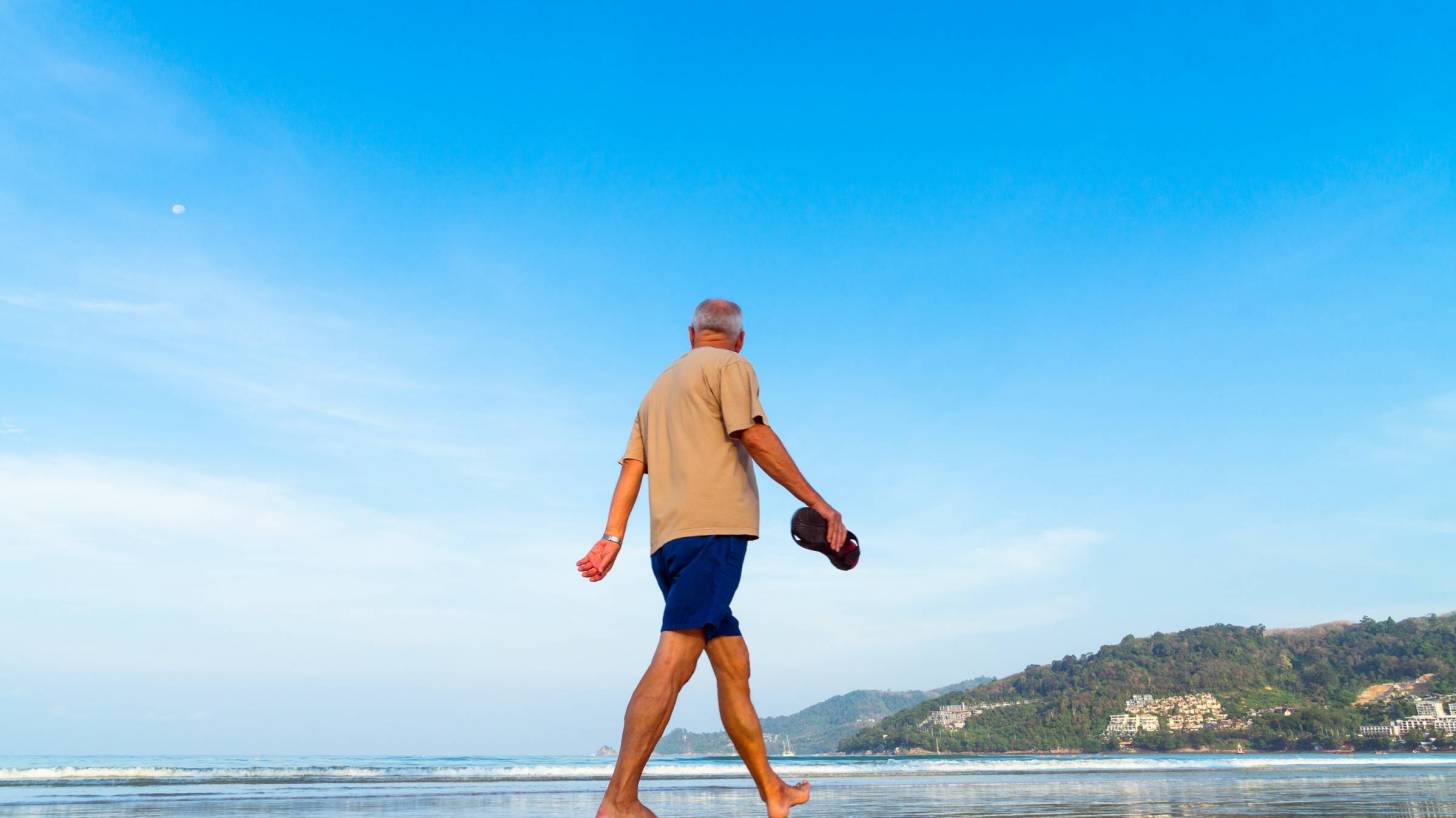 older man walking on a sunny beach