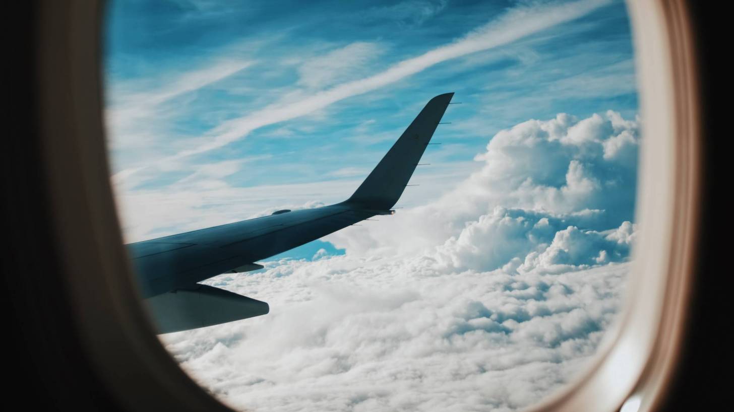 looking out airplane window towards the wing and clouds