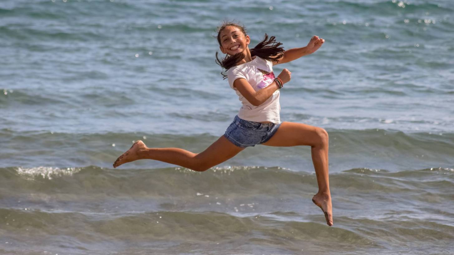 teen girl jumping for joy on a beach