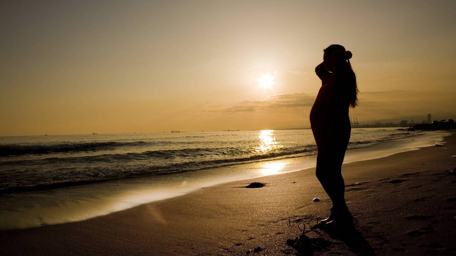 pregnant mom om beach at sunset