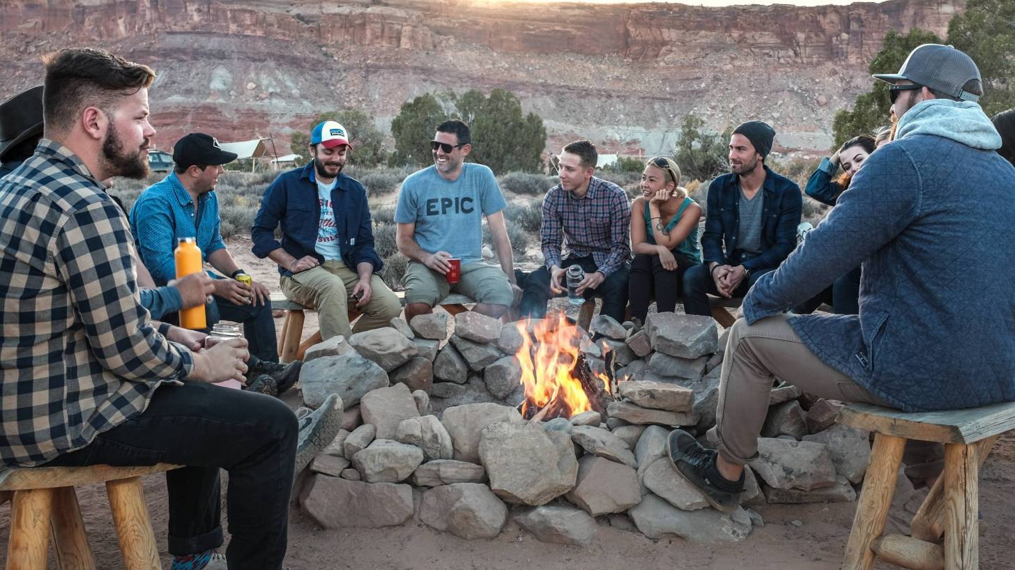 men sitting around an outdoor fire pit
