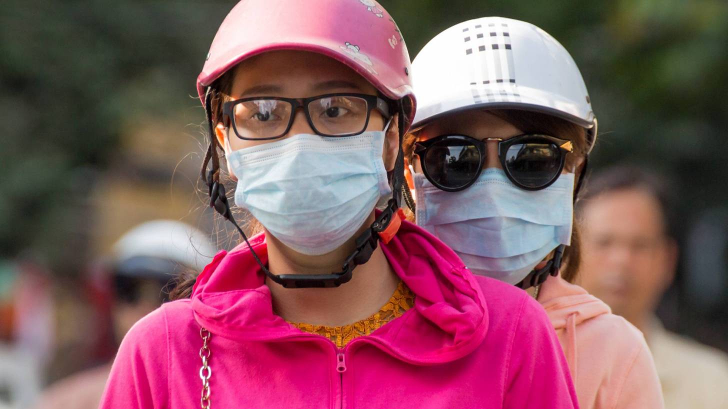 people with flu protective masks on a scooter