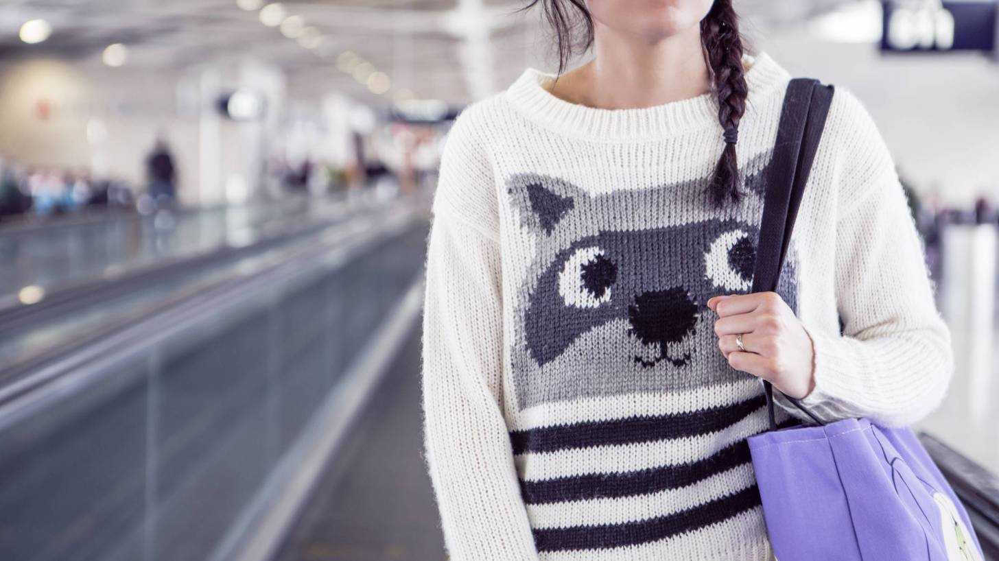women on airport walkway with funny sweater and eyes looking up