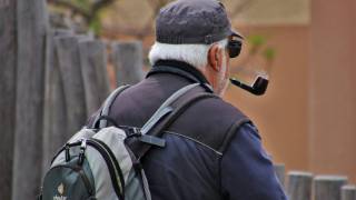 older man puffing on pipe taking a walk