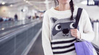 women on airport walkway with funny sweater and eyes looking up