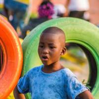 young boy happy standing by colored tires