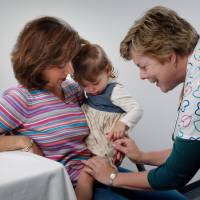 young child on moms lap getting a flu shot