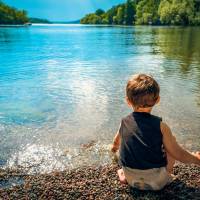 young child looking at a calm lake