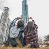 young couple sitting n the lawn looking at large buildings