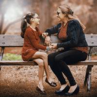 mom and daughter talking on a park bench
